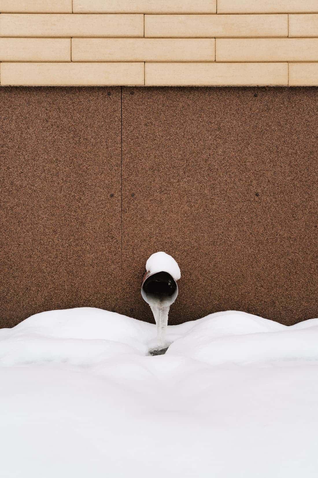 Pipe outside a building covered in snow
