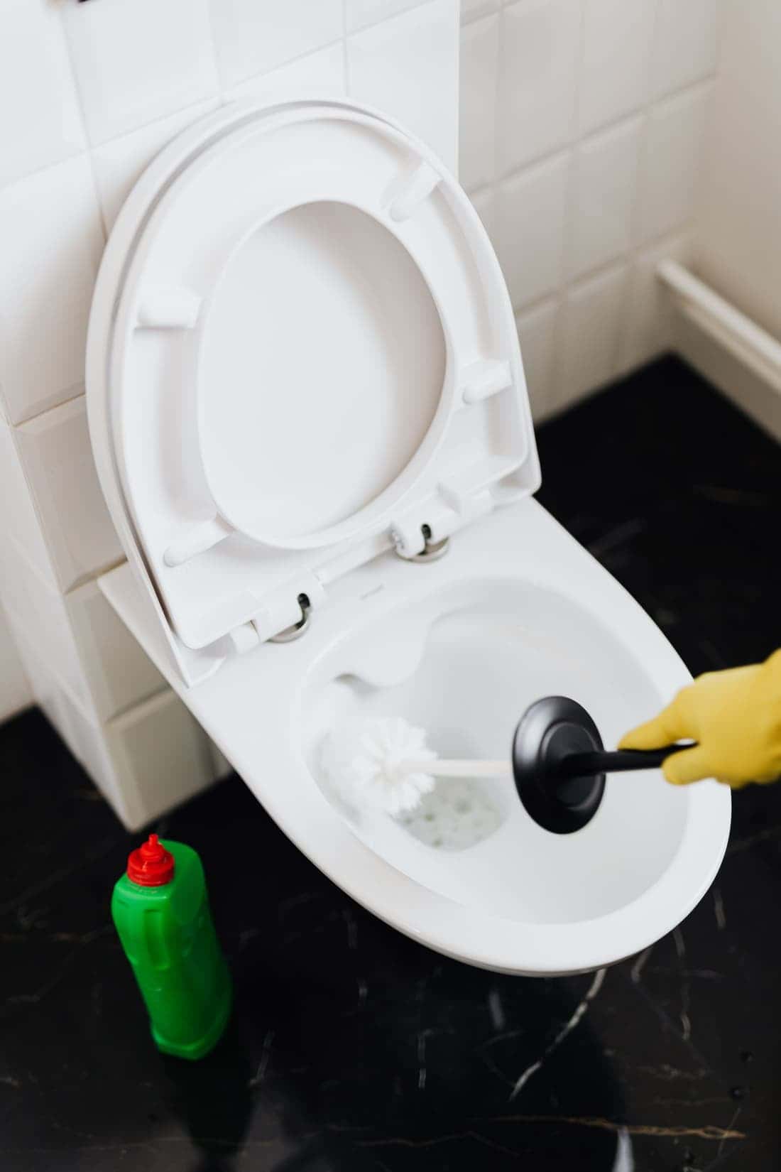 Gloved hand using a plunger to clear a clogged toilet