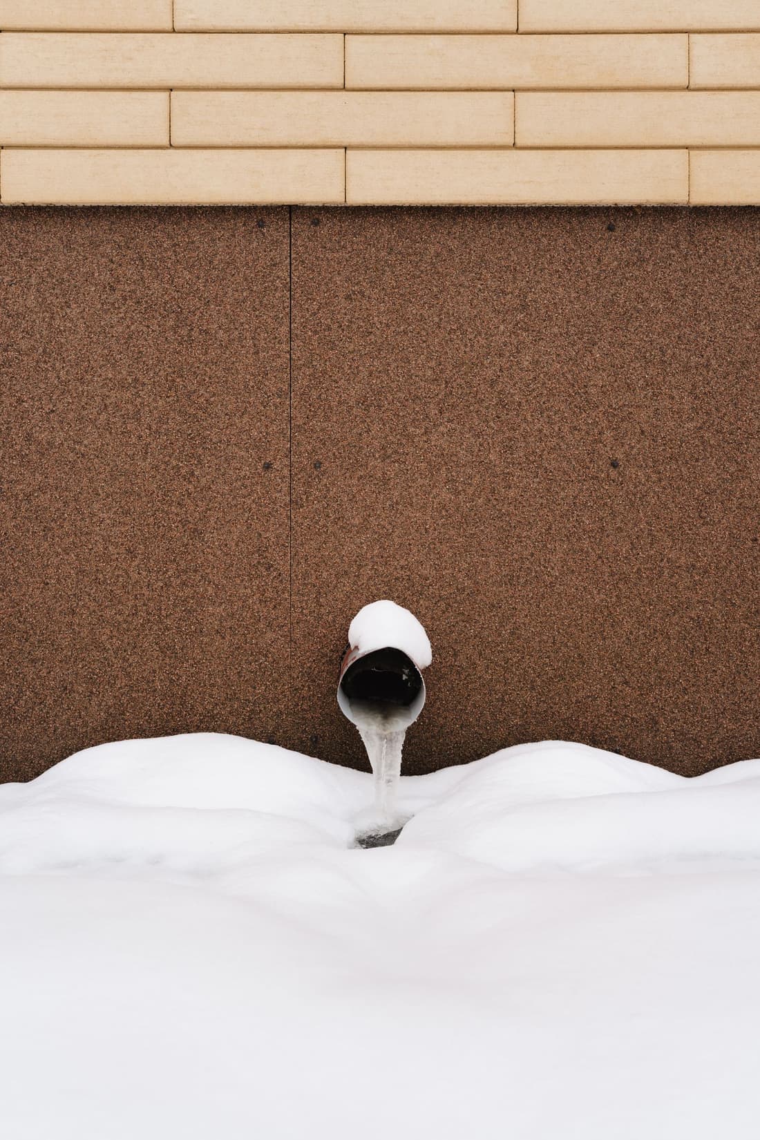 Pipe outside a building covered in snow